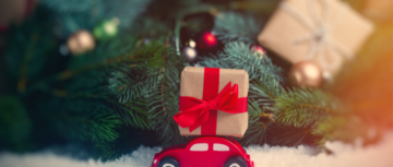 Petite voiture avec cadeau au pied d'un sapin de Noël